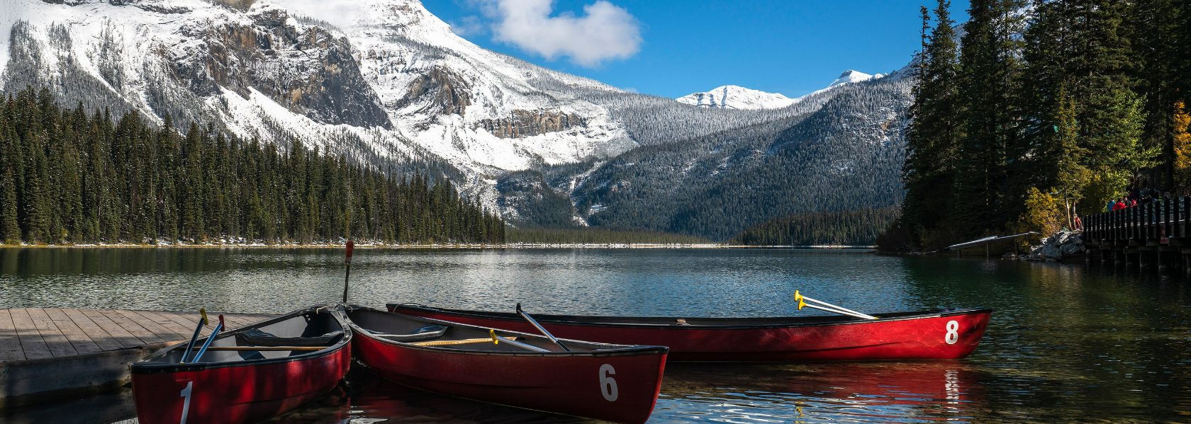 Red canoes moored at a dock on a mountain lake in the Canadian Rockies